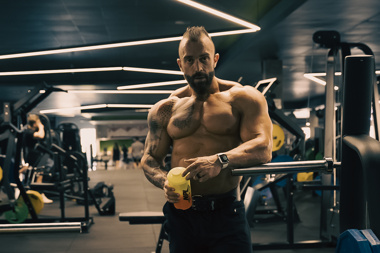 NPL athlete holding a water bottle leaning against a barbell, blog post is discussing the importance of protein and fibre in your diet